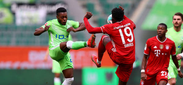WOLFSBURG, GERMANY - APRIL 17: Ridle Baku of VfL Wolfsburg is challenged by Alphonso Davies of FC Bayern Muenchen during the Bundesliga match between VfL Wolfsburg and FC Bayern Muenchen at Volkswagen Arena on April 17, 2021 in Wolfsburg, Germany. Sporting stadiums around Germany remain under strict restrictions due to the Coronavirus Pandemic as Government social distancing laws prohibit fans inside venues resulting in games being played behind closed doors. (Photo by Martin Rose/Getty Images)