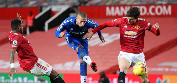 MANCHESTER, ENGLAND - FEBRUARY 06: Richarlison of Everton shoots under pressure from Fred and Victor Lindeloef of Manchester United during the Premier League match between Manchester United and Everton at Old Trafford on February 06, 2021 in Manchester, England. Sporting stadiums around the UK remain under strict restrictions due to the Coronavirus Pandemic as Government social distancing laws prohibit fans inside venues resulting in games being played behind closed doors. (Photo by Alex Pantling/Getty Images)