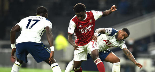 LONDON, ENGLAND - DECEMBER 06: Bukayo Saka of Arsenal is challenged by Steven Bergwijn of Tottenham Hotspur during the Premier League match between Tottenham Hotspur and Arsenal at Tottenham Hotspur Stadium on December 06, 2020 in London, England. A limited number of fans (2000) are welcomed back to stadiums to watch elite football across England. This was following easing of restrictions on spectators in tiers one and two areas only. (Photo by Glyn Kirk - Pool/Getty Images)